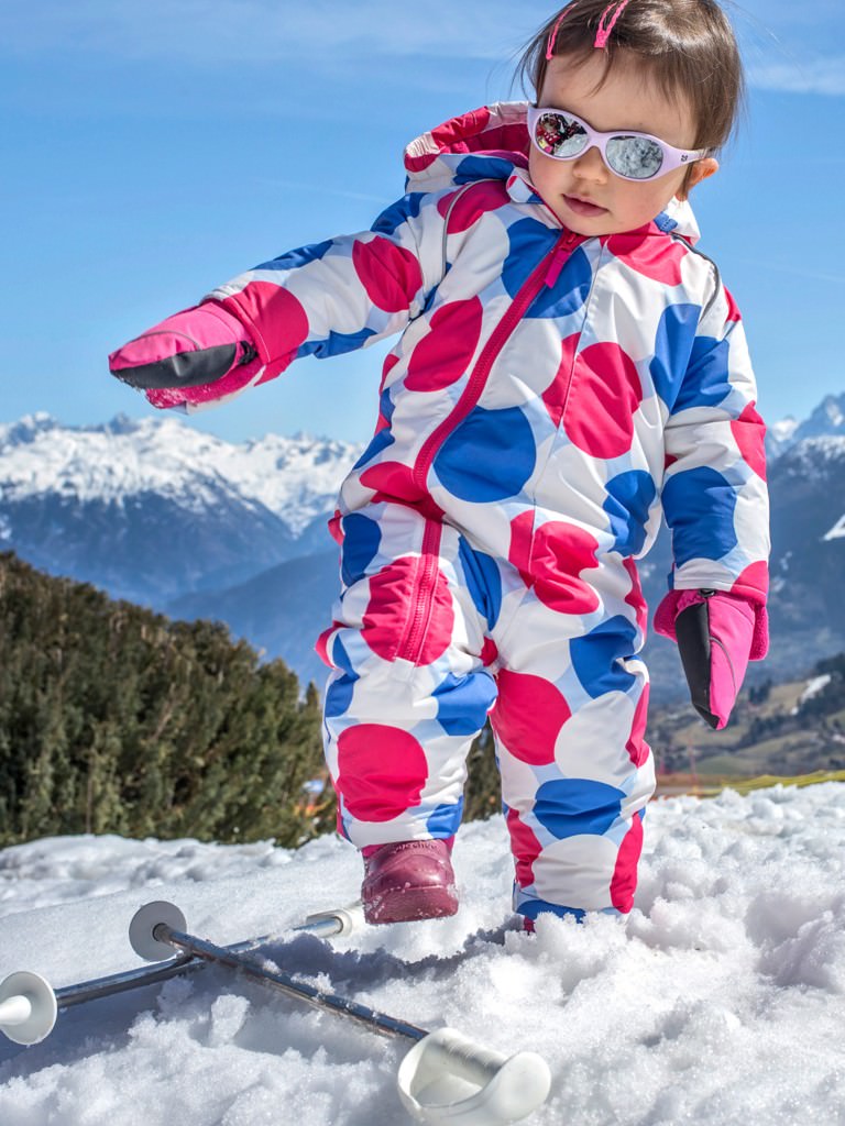 Child enjoying the snow in a ski onesie